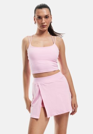 Rosa Zweiteiler bestehend aus einem kurzen Tanktop mit dünnen Trägern und einem passendem Rock mit einem Schlitz vorne, aus weichem, dehnbarem Material.