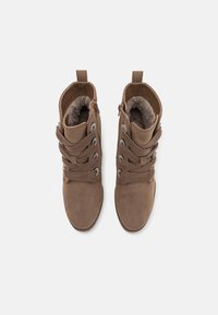 Bottines en daim marron avec une doublure en fausse fourrure, dotées de lacets décoratifs et d'une fermeture éclair sur le côté pour un enfilage facile.