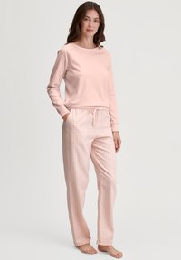 Lichtroze katoenen lounge set met een lange mouwen top en geruiten broek met een elastische tailleband en trekkoord.