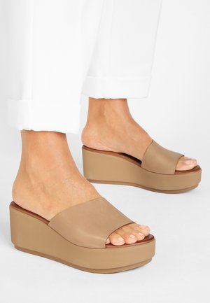 Beige wedge-sandaalit avoimella varpaalla, joissa on sileät nahkahihnat ja paksu pohja lisäkorkeutta varten.