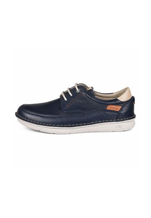 Zapato casual de cuero azul oscuro con suela blanca, detalle beige en el talón y cordones blancos, mostrado de lado sobre un fondo blanco.