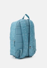 Ljusblå vadderad ryggsäck med ett upprepande Nike-logomönster, justerbara axelremmar och en framficka med dragkedja samt en hållbar textur.
