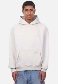 Weißer Kapuzenpullover mit Kängurutasche, lockerer Passform und gerippten Bündchen. Baumwollmischung, weiche Textur, minimale Markenpräsenz.