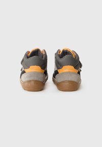 Pair of gray and orange toddler shoes with brown soles facing backward on a white background.