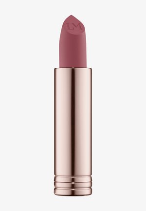 Matte lipstick in a light mauve shade with a pointed tip, housed in a glossy rose gold tube featuring textured details and a curved base.