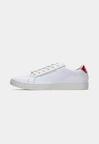Adidași sintetici albi cu un finisaj neted, având un accent roșu la călcâi și o talpă gri deschis. Șireturile și brandingul metallic sunt vizibile pe lateral.