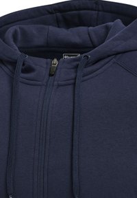 Felpa con zip di colore blu navy, dotata di cappuccio con cordino, texture morbida e dettagli cuciti lungo le spalle e la zip frontale.