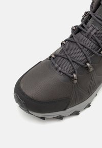 Szare buty trekkingowe z teksturowaną skórzaną cholewką, siateczkowymi wstawkami, wzmocnionym noskiem oraz gumową podeszwą z wypustkami zapewniającymi przyczepność.