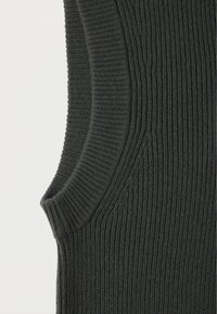 Top sin mangas de color gris oscuro con textura acanalada, cuello alto y orificios para los brazos curvados, con una textura suave y un patrón uniforme en todo el tejido.