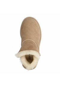 Tan suède enkellaars met een ronde neus, fleecevoering en zachte bies rond de opening. Platte zool met zichtbare stiksels langs de randen.