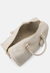 Beige leather duffel bag with gold zipper, double handles, and a spacious interior. Features minimalist design and smooth texture.