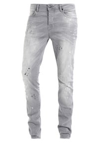 Grå denimjeans med smal passform, med slitna områden och färgsplatter i svart och vitt. Standard femficksdesign med knappstängning.