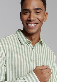 Gestreept shirt in lichtgroen en wit, gemaakt van een textured stof, met een kraag en knoopsluiting. Smal model.