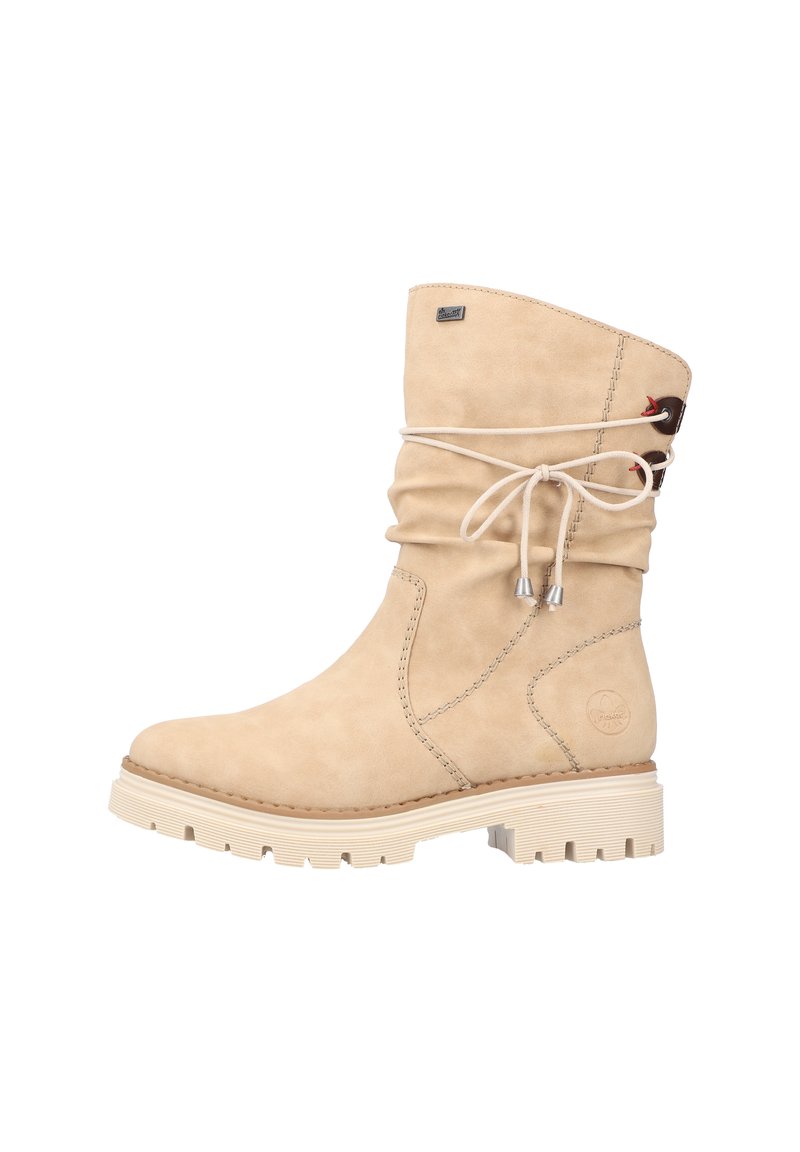 Bottine en daim beige à design lâche, bout rond, semelle en caoutchouc blanc contrastant et détail de lacet décoratif en haut.