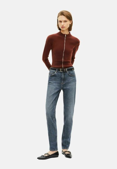 Sudadera burdeos con cremallera, ajuste Slim, combinada con jeans azules de tiro medio. Zapatos planos negros con lazos. Texturas simples y suaves y diseño casual.