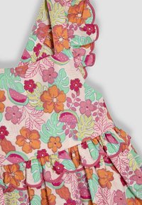Robe à motif floral avec une base rose, des bretelles volantées, des accents orange et verts, et une jupe superposée avec des bords festonnés.