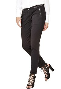 Pantalons noirs ajustés avec poches avant, détails studds sur les hanches, associés à des sandales à talons hauts noires à lanières.