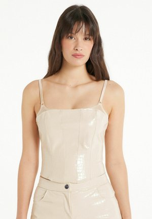 Haut cropped en simili cuir beige avec décolleté carré, fines bretelles et un motif texturé ressemblant à la peau de crocodile.
