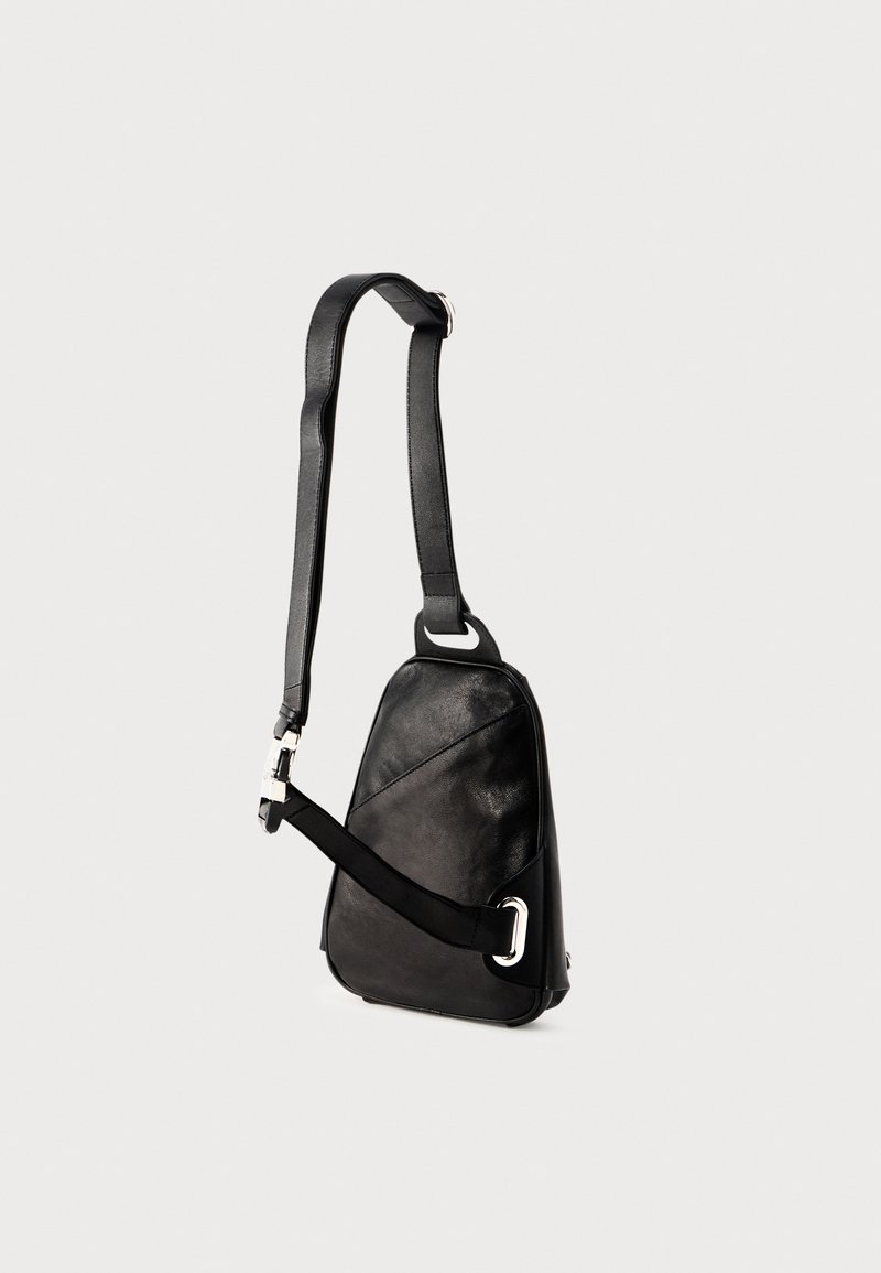 Black leather crossbody bag with a geometric shape, featuring a single adjustable strap and silver-tone hardware accents.