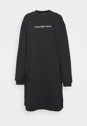 Czarna, codzienna sukienka z długim rękawem, z prążkowanymi mankietami i dekoltem, z białym napisem "Calvin Klein Jeans" na piersi.