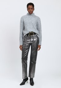 Lys grå fluffy turtleneck sweater parret med skinnende metallic sølv lige ben bukser. Sort bælte med en rund spænde og sorte ankelstøvler.