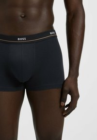 Black fitted boxer briefs with a soft waistband featuring "BOSS" logo in white, showing smooth fabric and a snug design.