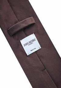 Brunrandig slips i texturerat tyg. Har en vit märkesetikett med texten "JOHN HENRIC SWEDEN" och "Tillverkad i Italien."