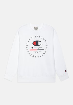 Sudadera blanca con un logo redondo en negro y rojo, texto "Champion" y puños acanalados. Fabricada con tela suave, presenta un corte clásico en el cuello.