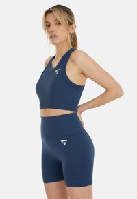 Navyblaues, geripptes Sportbekleidungsset mit einem ärmellosen Cropped-Top und hoch geschnittenen Shorts, beide mit einem dezenten Logodetail.