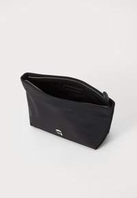 Čierny nylonový obal so zipsovým uzáverom, obdĺžnikový tvar, hladký povrch, na prednej strane má malé strieborné logo. Pohľad zhora otvorený.