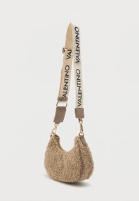 Bežs mākslīgās vilnas rokassoma ar izliekta forma. Iepakojumā ir bežs siksniņš ar melnu "VALENTINO" zīmolu un zelta toņu aparatūras akcentiem.