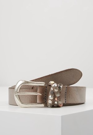 Jasnobrązowy skórzany pasek z srebrną sprzączką i ozdobnym paskiem z metalowymi ćwiekami w kolorze srebrnym i złotym, ułożony w spiralę na białej powierzchni.