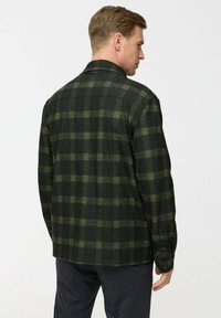 Green and black plaid shirt, made of textured fabric, featuring a button-down collar and buttoned cuffs, seen from the back.