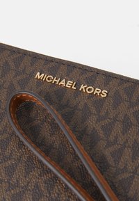 Barna mintás Michael Kors táska, texturált felülettel és arany logóval. Tartós bőrszíjjal rendelkezik a hordozáshoz.
