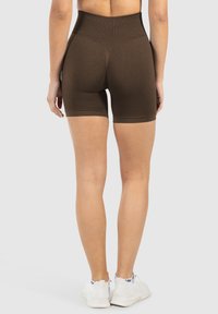 Bruine high-waisted shorts van rekbaar materiaal. Kenmerkt zich door textuurdetails langs de zijkanten en een aansluitende, gladde tailleband.