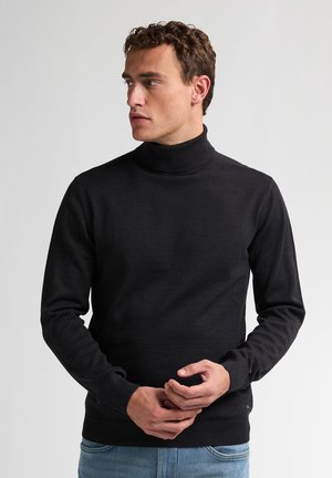 Zwarte coltrui gemaakt van een glad materiaal met lange mouwen en een geribde kraag, gecombineerd met lichtblauwe jeans.
