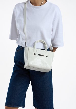 Petit sac à main blanc avec un design texturé en motif crocodile, deux poignées et une sangle réglable pour un port en bandoulière.