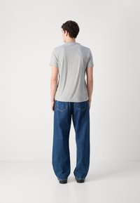 Gray short-sleeve t-shirt paired with oversized blue denim jeans. The shirt's fabric is smooth, while the jeans are slightly baggy with visible pockets.