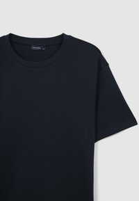 T-shirt di cotone blu navy con scollatura rotonda, maniche corte e una texture liscia senza motivi o decorazioni visibili.