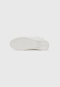 White sneaker sole with a textured surface, featuring a circular logo and two horizontal lines near the toe. Smooth, rubbery material.