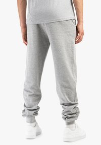 Gray cotton sweatpants with elastic cuffs, featuring a relaxed fit and side pockets, paired with white sneakers.
