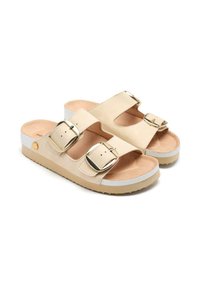 Sandalias beige con doble hebilla ajustable, plantilla suave y suela gruesa con un fondo texturizado y una franja blanca de acento.