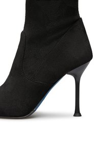 Stivale ankle in suede nero con silhouette affusolata, dotato di un alto tacco a stiletto e una suola blu liscia. I dettagli delle cuciture aggiungono una sottile texture.