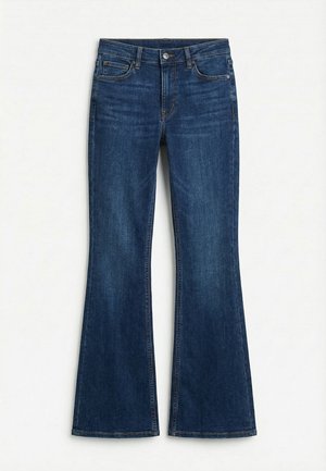 Σκούρο μπλε τζιν με ελαφρώς φαρδύ πόδι, με κούμπωμα με κουμπιά και φερμουάρ μπροστά και σχεδίαση με πέντε τσέπες, απλωμένο σε ανοιχτό φόντο.