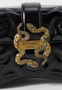 Sac à main en cuir noir avec des motifs de vagues en relief et un fermoir en forme de serpent doré avec une plaque logo rectangulaire.