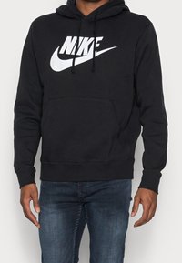 Sudadera negra de tela suave, que presenta un bolsillo tipo canguro en la parte delantera, cordones y un gran logo de Nike en blanco en el pecho.