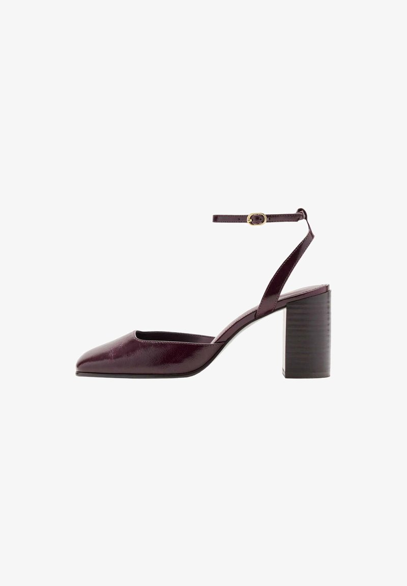 Chaussure à talon haut violet foncé avec un bout pointu, un talon bloc et une bride à la cheville avec une petite boucle dorée.