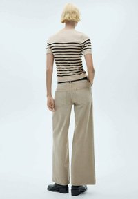 Beige wide-leg trousers and a fitted striped top in beige and black. The outfit features a minimalist design with visible stitching details.