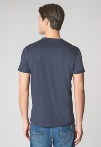 T-shirt in cotone blu navy con maniche corte, scollo rotondo e orlo dritto, abbinato a jeans in denim blu medio. Texture liscia.