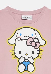 Roza bombažna majica s kratkimi rokavi s karikaturalno grafiko lika z lokom in zajcem na vrhu, obrobljena z rumeno. Dizajn z okroglim izrezom na vratu.